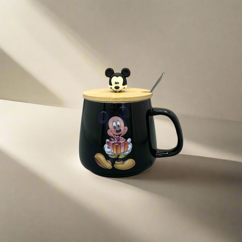 Black mug with a gold lid featuring cartoon characters on a white surface