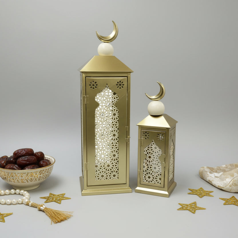Decorative gold lanterns with intricate cut-out patterns on a gray wall.